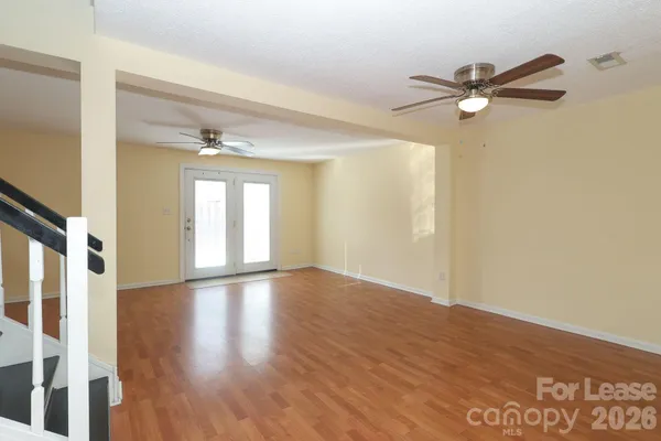 a view of empty room with wooden floor and fan