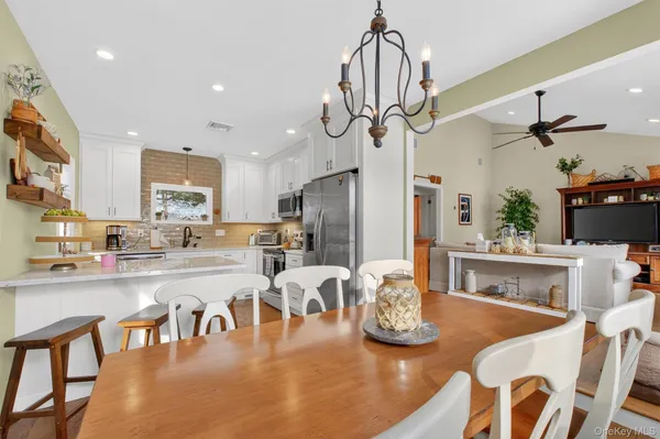 a view of a dining room and livingroom with furniture wooden floor a chandelier