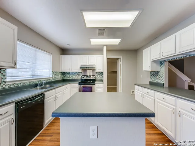 a kitchen with kitchen island granite countertop a sink counter top space cabinets and stainless steel appliances