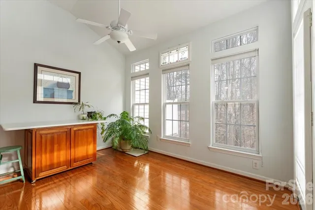 a view of an empty room with window wooden floor and a kitchen space