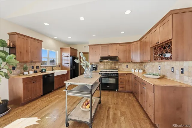 a kitchen with stainless steel appliances kitchen island granite countertop a stove top oven a sink a refrigerator and white cabinets