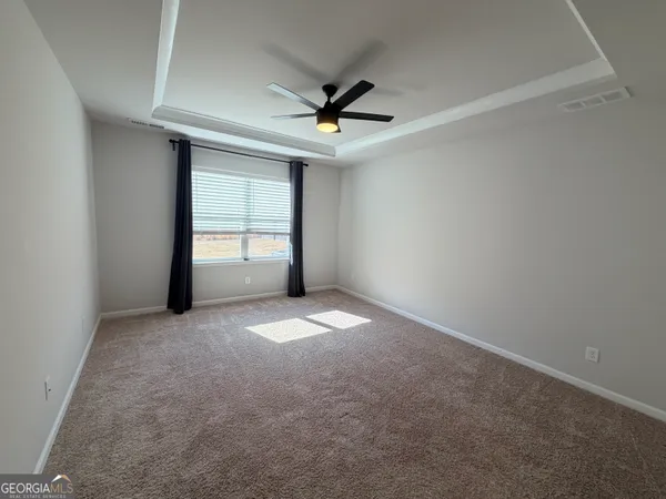 an empty room with windows and ceiling fan