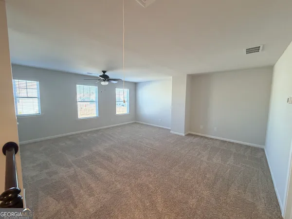 an empty room with windows and ceiling fan view