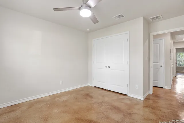 an empty room with closet and a chandelier fan