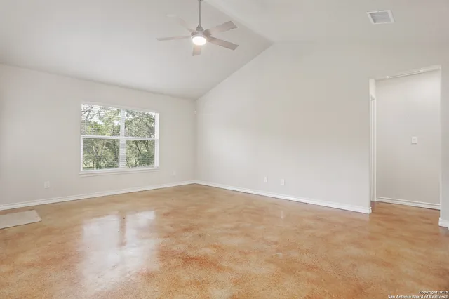 an empty room with windows and ceiling fan
