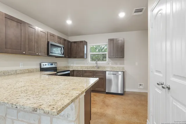a kitchen with stainless steel appliances granite countertop a sink stove and refrigerator