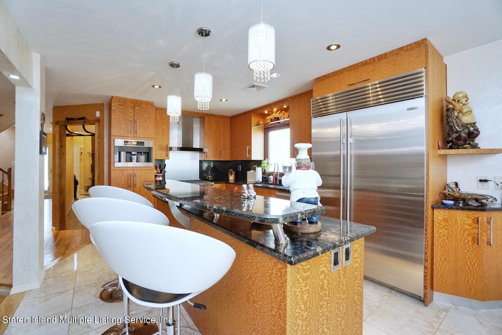 67 Covington Circle Staten Island, NY 10312 - Photo 16 of 45 a kitchen with stainless steel appliances kitchen island granite countertop a table chairs in it and wooden floors