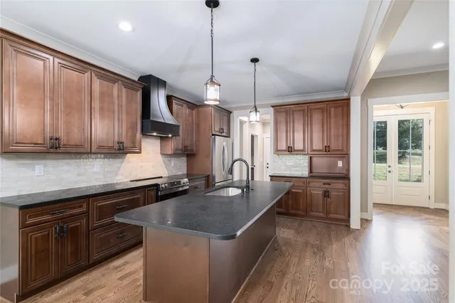 a kitchen with stainless steel appliances granite countertop a sink a stove and refrigerator
