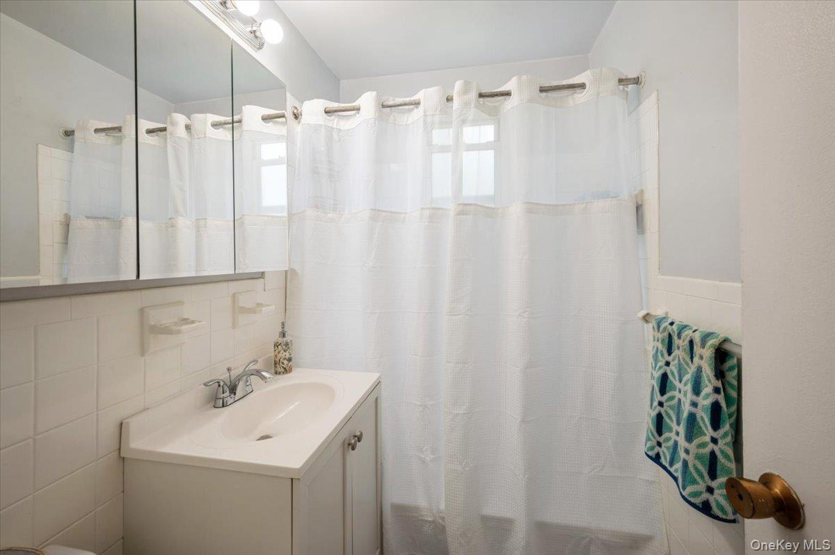 120 Dehaven Drive, Unit 629 Yonkers, NY 10703 - Photo 7 of 12 Bathroom with vanity, tile walls, curtained shower, and backsplash