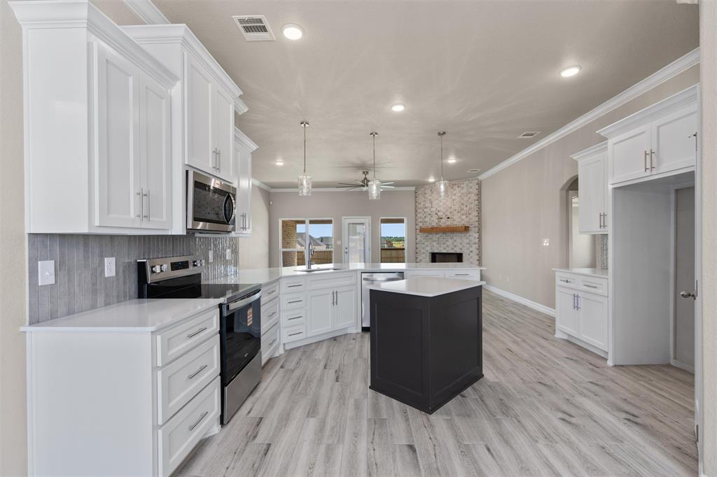 1341 Promised Land Road Hewitt, TX 76643 - Photo 5 of 29 Modern kitchen featuring white cabinetry, quartz countertops, a dark-toned island, stainless steel appliances