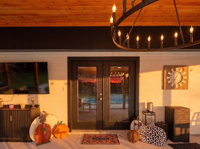 1114 Wagon Road Simonton, TX 77485 - Photo 18 of 48 Charming outdoor space with elegant double doors leading to a pool area, highlighted by a stylish chandelier and cozy decor accents.