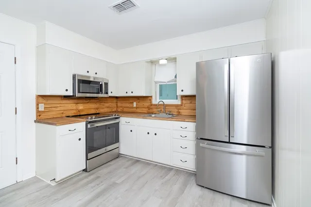 a view of a kitchen with white cabinets and refrigerator