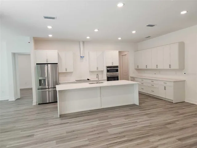 a large kitchen with a center island stainless steel appliances and cabinets