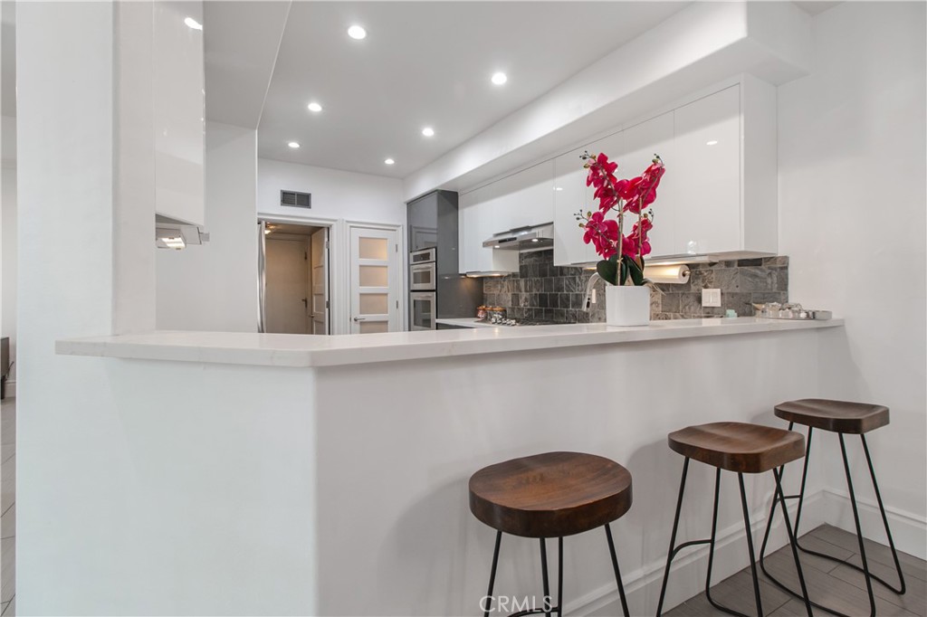 23057 Park Este Calabasas, CA 91302 - Photo 16 of 31 a kitchen with granite countertop a dining table chairs and a potted plant