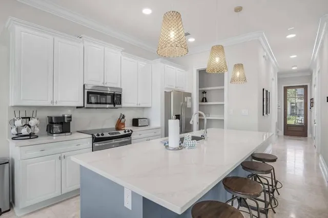 a kitchen with stainless steel appliances kitchen island granite countertop a table chairs sink and cabinets