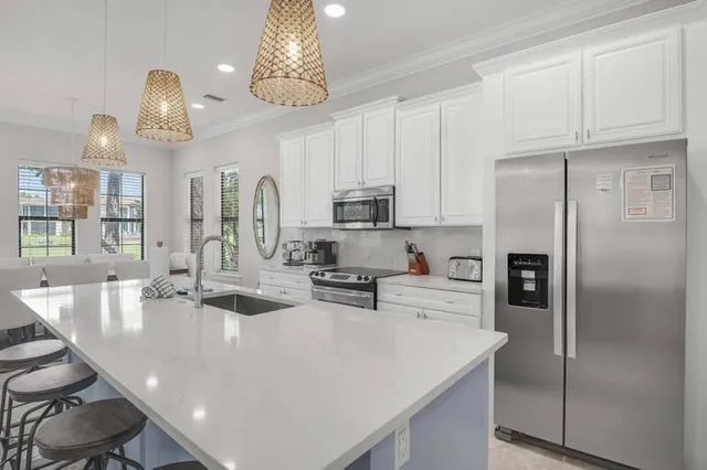 a kitchen with stainless steel appliances granite countertop a refrigerator a sink a stove and chairs
