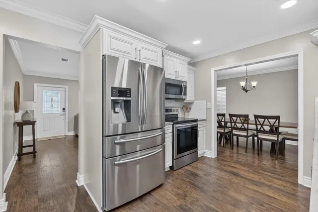 a kitchen with stainless steel appliances wooden floor and a refrigerator