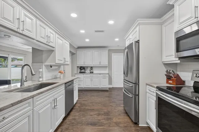 a kitchen with white cabinets and stainless steel appliances