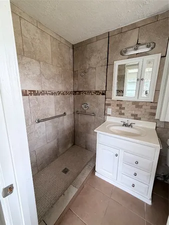 a bathroom with a granite countertop sink a mirror and shower