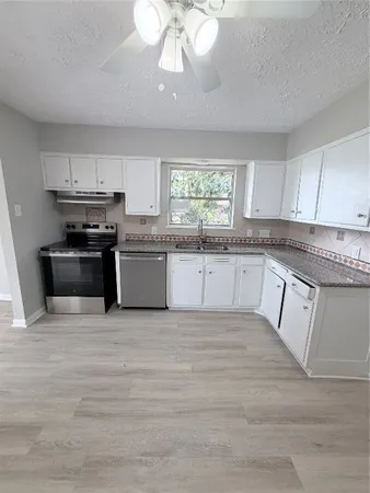 a large kitchen with granite countertop a stove top oven a sink and dishwasher