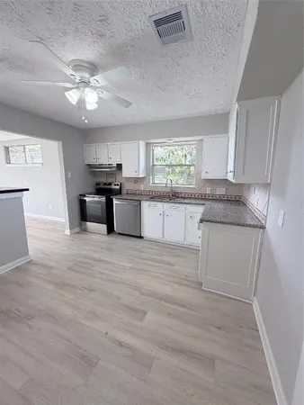 a kitchen with stainless steel appliances granite countertop a stove cabinets and chandelier