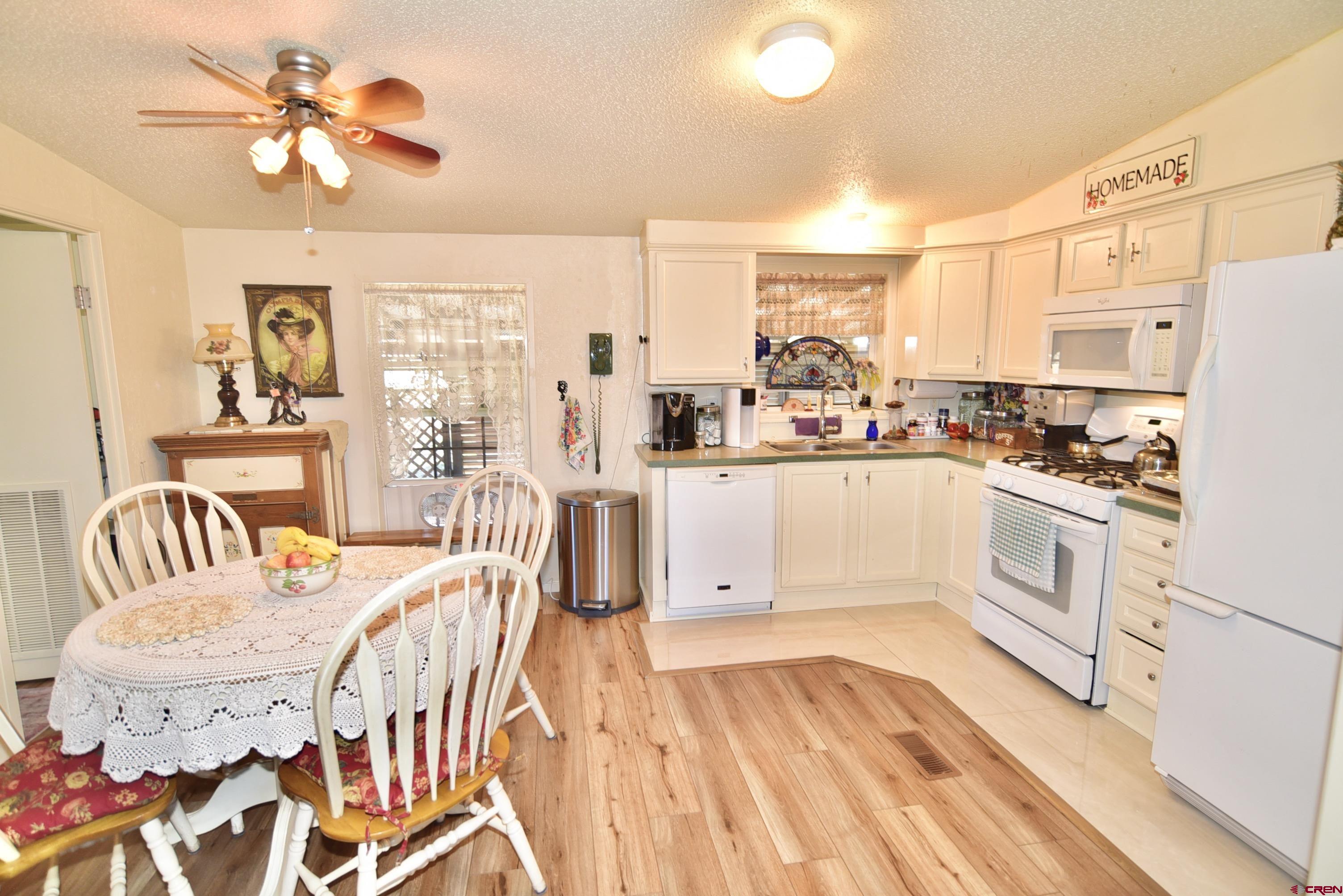 20020 Kenosha Road Austin, CO 81410 - Photo 7 of 40 a large white kitchen with a stove a sink dishwasher and a refrigerator with wooden floor
