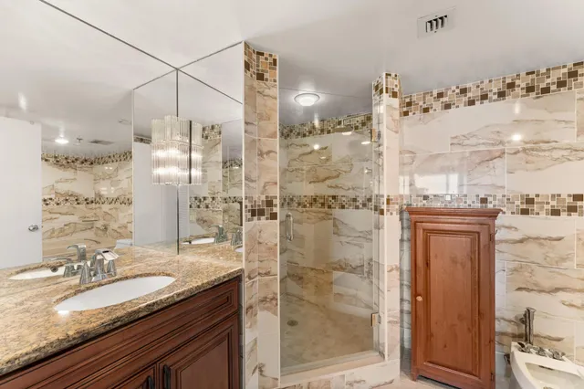 a bathroom with a granite countertop sink a mirror and shower