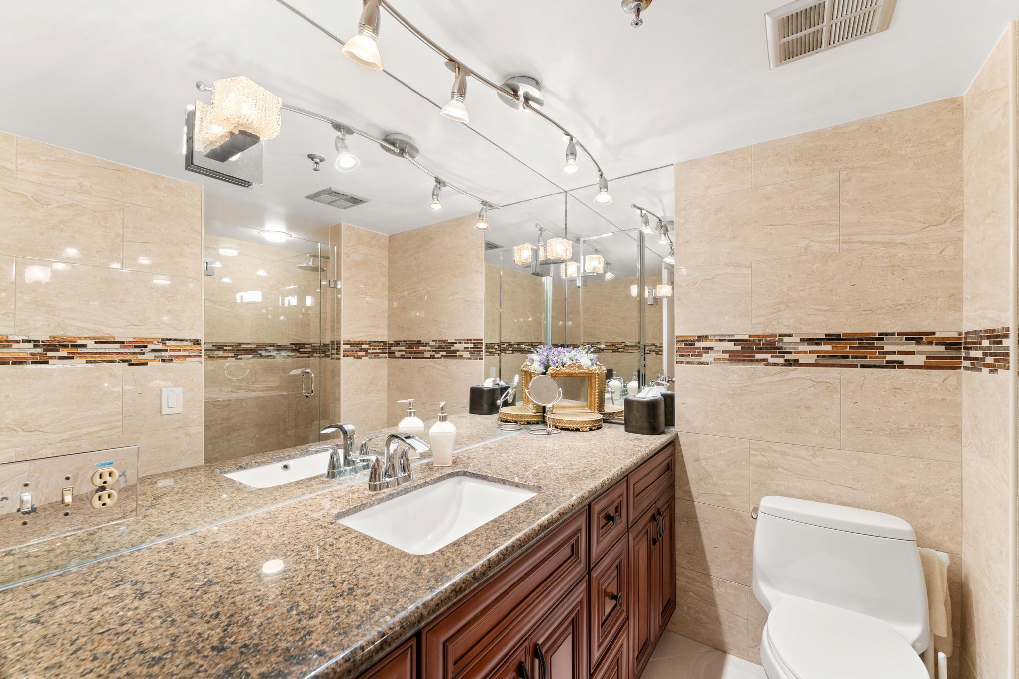 1900 Consulate Place, Unit 2002 West Palm Beach, FL 33401 - Photo 21 of 29 a bathroom with a granite countertop sink a toilet and a mirror