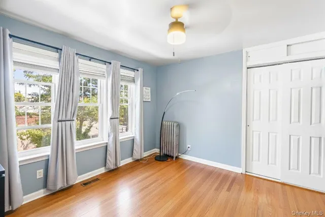 a view of an empty room with window and wooden floor
