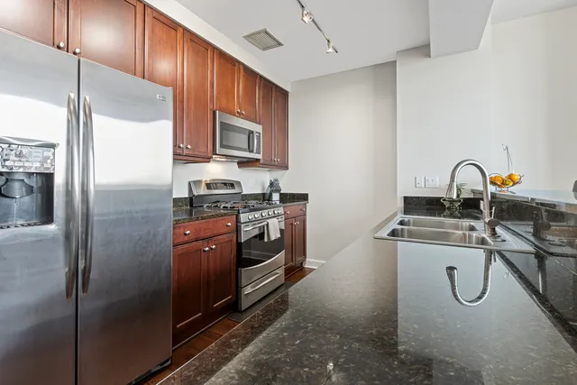 a kitchen with stainless steel appliances granite countertop a refrigerator and a stove top oven