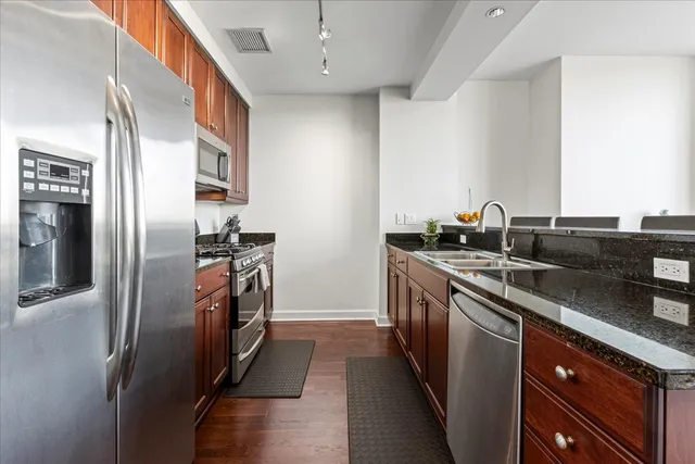 a kitchen with stainless steel appliances granite countertop a refrigerator and a sink
