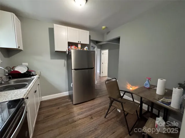 a kitchen with stainless steel appliances granite countertop a refrigerator a stove a sink dishwasher and a refrigerator with wooden floor