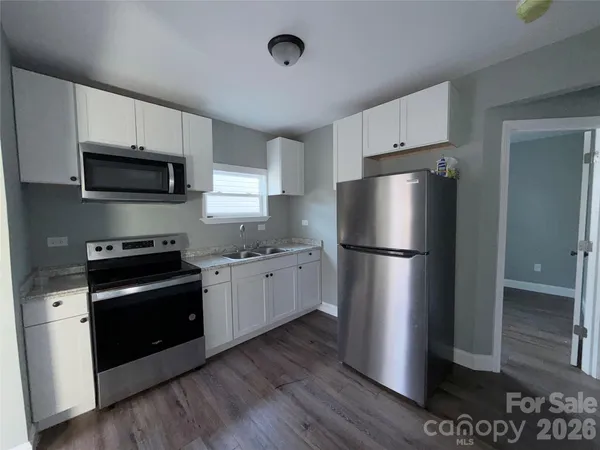 a kitchen with stainless steel appliances granite countertop a refrigerator a stove a sink and a granite counter tops with wooden floors
