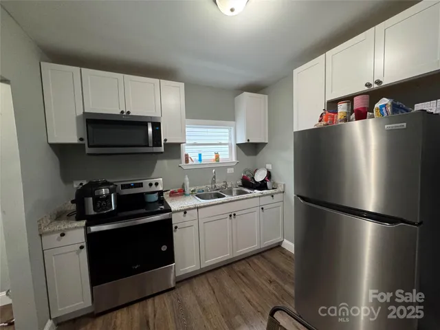 a kitchen with a refrigerator stove and sink with wooden floor