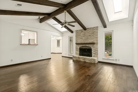 an empty room with wooden floor fireplace and windows