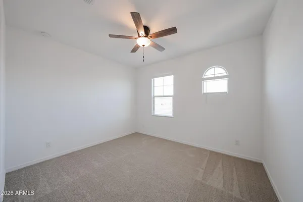 an empty room with windows and ceiling fan
