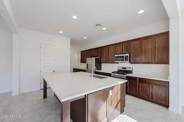 a kitchen with stainless steel appliances a stove top oven a refrigerator a sink a stove top oven and a center island