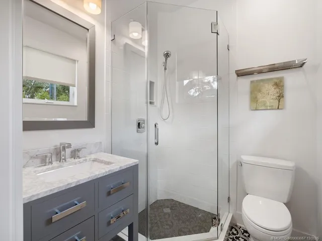 a bathroom with a granite countertop sink a toilet a shower and a mirror