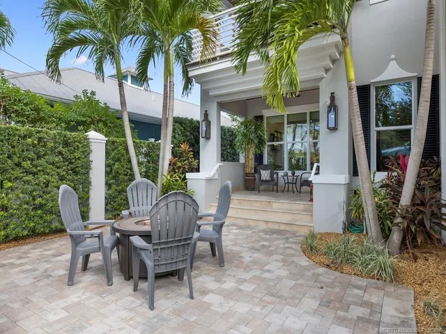 a view of a patio with table and chairs potted plants and floor to ceiling window