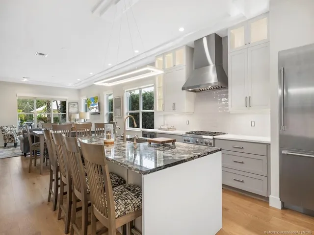 a kitchen with stainless steel appliances granite countertop a stove a refrigerator a dining table and chairs