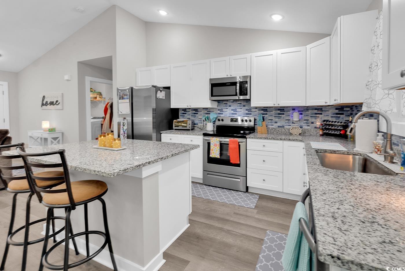 1517 Ackerrose Drive Conway, SC 29527 - Photo 11 of 33 Kitchen featuring stainless steel appliances, a breakfast bar, tasteful backsplash, a center island, and white cabinetry