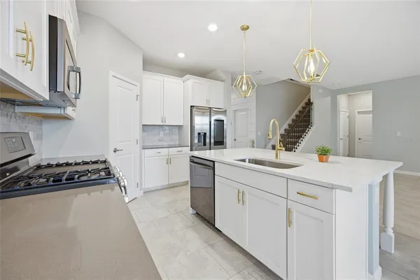 a kitchen with kitchen island granite countertop a sink a stove and cabinets