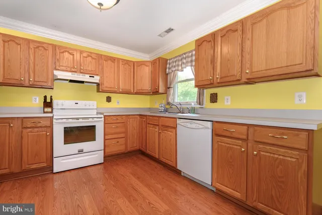 a kitchen with granite countertop wooden cabinets stainless steel appliances a sink and a window