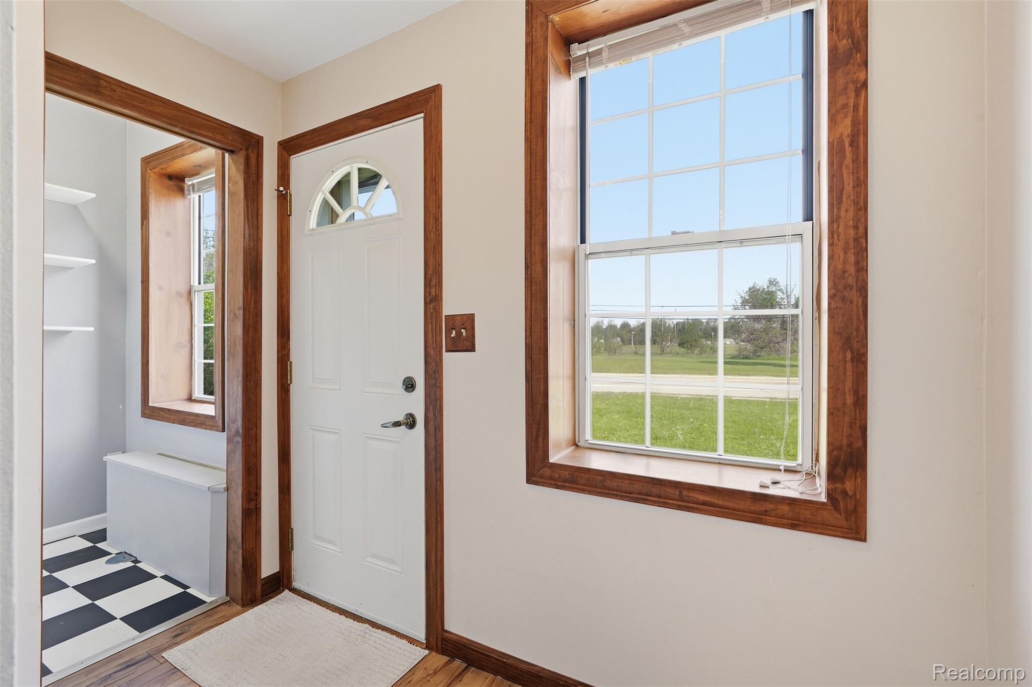5634 Chicago Road Warren, MI 48092 - Photo 4 of 36 Entryway featuring a white paneled door with an arched glass insert, rich wood trim around doors and windows, light-toned wall paint, and wood-finish flooring