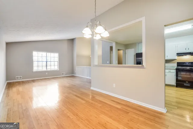 a view of an empty room with window and wooden floor