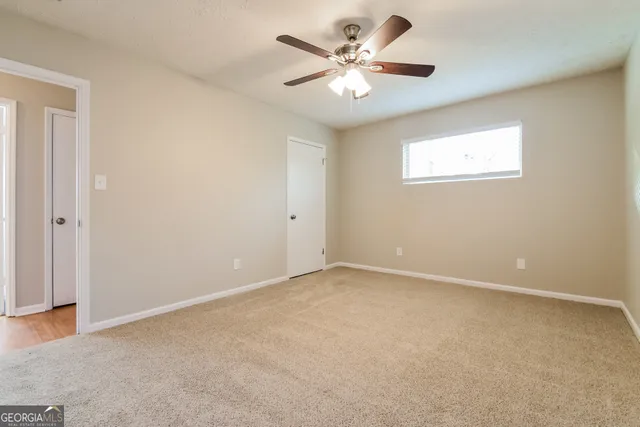an empty room with a chandelier fan and windows
