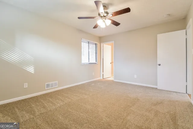 an empty room with windows and fan