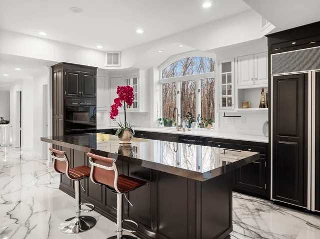 a kitchen with stainless steel appliances kitchen island granite countertop a refrigerator a stove and a dining table with wooden floor