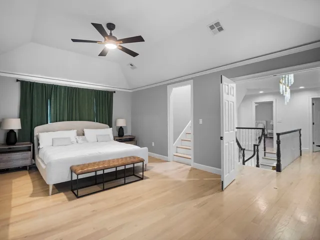 a spacious bedroom with a bed a table and ceiling fan