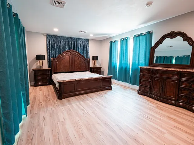 a spacious bedroom with a bed lamp and a dresser